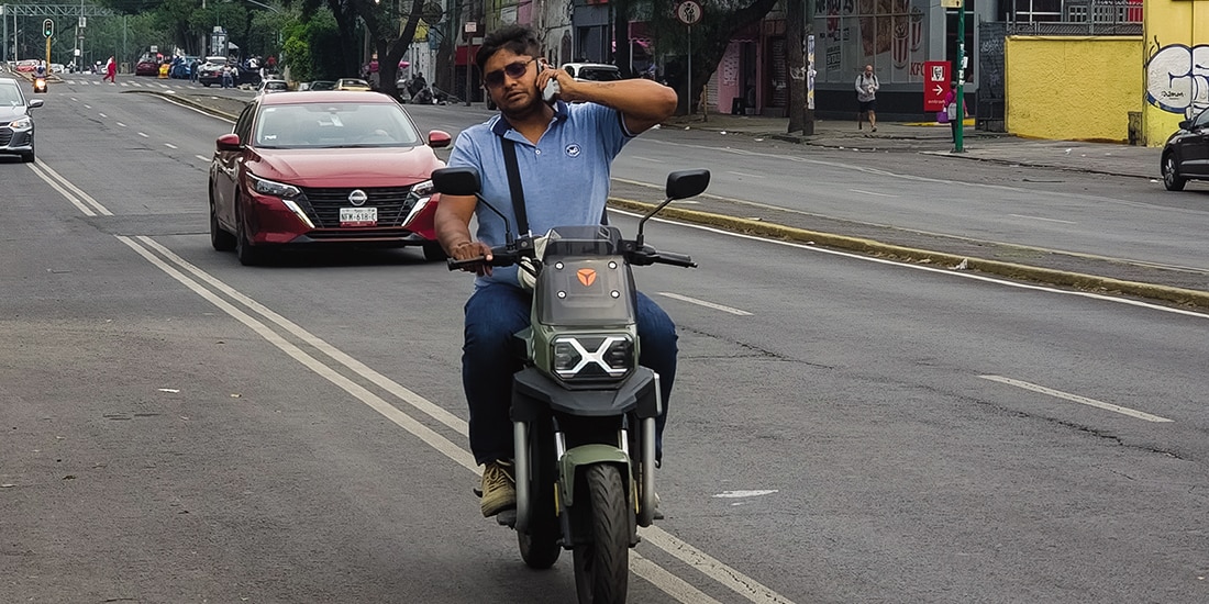 UN HOMBRE conduce una moto eléctrica, sin casco y al teléfono, el 5 de mayo