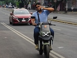UN HOMBRE conduce una moto eléctrica, sin casco y al teléfono, el 5 de mayo