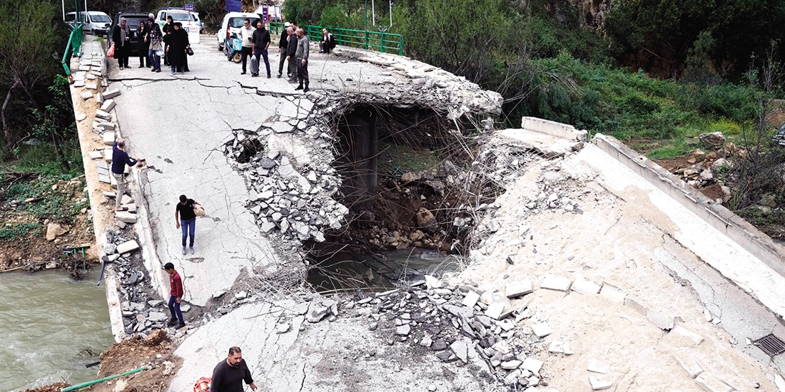 Personas desplazadas cruzan un puente destruido en la aldea de Tayr Felsay, al sur del Líbano, ayer.